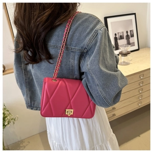 Close-up of fuchsia quilted chain crossbody bag with golden twist lock on a model