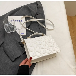 Detail shot of white geometric 3D embossed crossbody bag on a stylish grey blazer