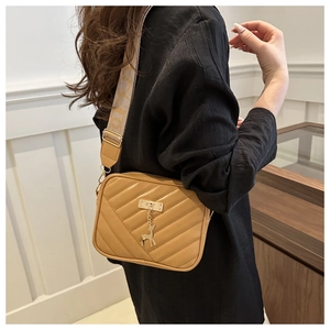 Close-up of khaki quilted crossbody bag with jacquard strap and deer metal pendant