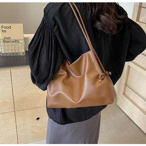 Close-up of caramel brown shoulder bag with soft pleated texture and knot detail