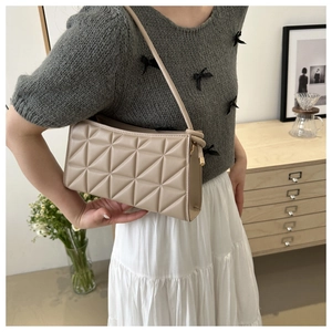 Detail of beige quilted faux leather crossbody bag with geometric stitching patterns