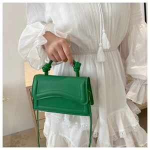 Detail of lime green crossbody bag featuring a unique knotted handle and wave stitching