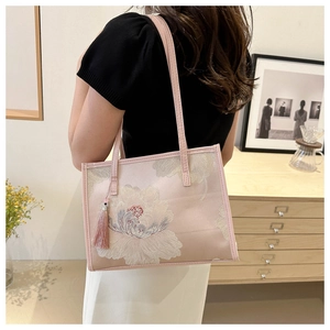 Gros plan du sac cabas rose avec broderie florale et détail de pompon en soie