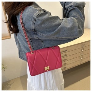Detail of rose red quilted crossbody bag with gold chain strap and turn-lock closure