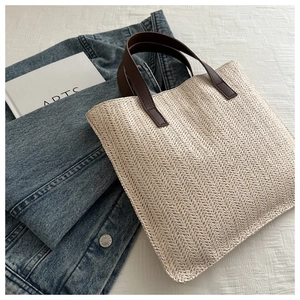 Close-up of beige herringbone weave texture and brown leather handles on tote bag