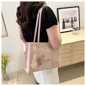 Détail du sac cabas rose montrant une broderie florale exquise et un gland assorti