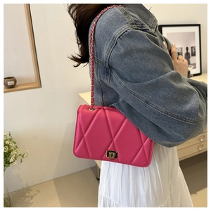 Detail of rose red quilted crossbody bag featuring gold chain strap and metal clasp