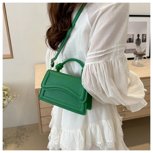 Detail of a bright green leather handbag with wavy embossed flap and knotted handle detail