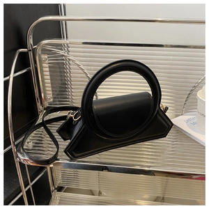 Dettaglio di una borsa a trapezio nera geometrica con grande manico tondo e tracolla in pelle