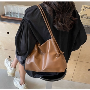Close-up of caramel brown leather tote bag with unique knot detail and slim shoulder straps