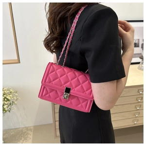 Detail of a bright magenta quilted crossbody bag with silver twist lock on female model