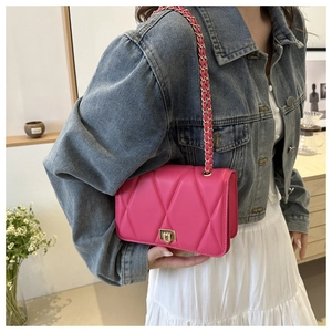 Detail of rose pink quilted crossbody bag with gold chain strap on female model