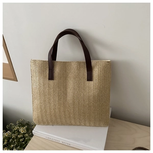 Detail of minimalist straw tote bag with herringbone weave and brown leather handle