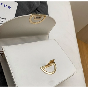 Detail of white leather crossbody bag with golden semicircular rotary metal lock