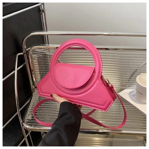 Dettaglio di una borsa a trapezio rosa acceso con manico circolare e hardware oro