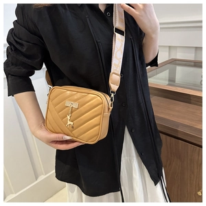Detail of light brown quilted square bag with deer charm and jacquard wide strap