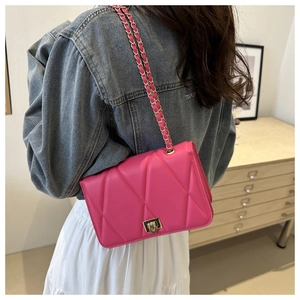 Detail of rose pink crossbody bag with gold chain strap and V-shaped stitching detail