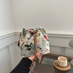 Bohemian floral jacquard drawstring bucket bag with brown leather strap held by a person
