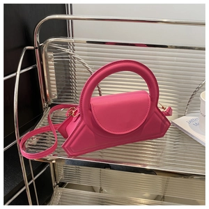 Dettaglio della borsa a mano trapezoidale rosa con manico rotondo e hardware dorato