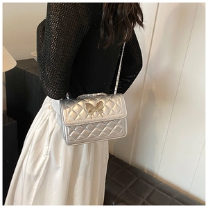 Détail du sac bandoulière argenté matelassé avec fermoir papillon doré et bandoulière chaîne