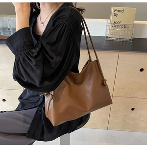 Close-up of brown soft leather shoulder bag with decorative knot detail on the strap
