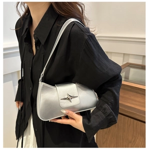 On-shoulder view of a matte silver underarm bag featuring a metallic star buckle