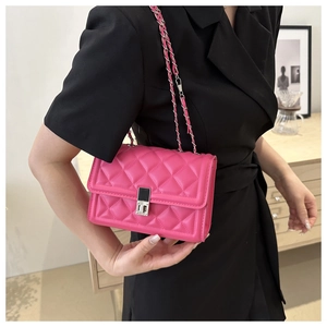 Close-up of hot pink quilted crossbody bag with silver rotary lock and chain strap