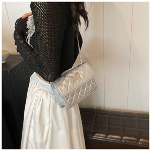 Détail du sac bandoulière argenté matelassé avec fermoir papillon et chaîne