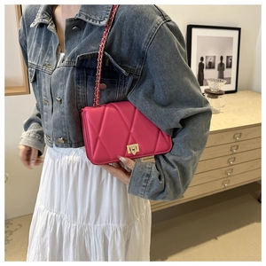 Close-up of rose pink quilted chain bag with gold metal clasp on a model shoulder