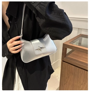 Detail of silver metallic underarm bag featuring a trendy star buckle on the flap