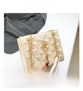 Detail of off-white geometric embossed handbag with gold chain and S-shaped tassel charm