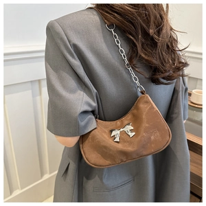 Brown crescent armpit bag with metallic bow and silver chain strap for women