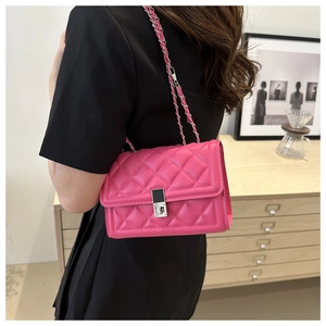 Magenta quilted crossbody bag with silver chain strap shown worn on a model's side