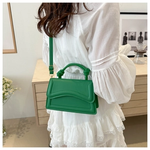 Detail of a bright green leather handbag with U-shaped embossing and knotted handle detail