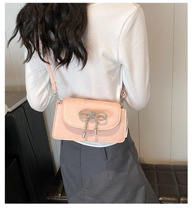 Pink crossbody envelope bag with rhinestone bow detail and metallic tassels on a model