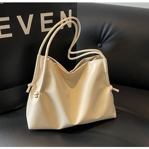 Detail of cream shoulder bag featuring side drawstring pleats and slim straps