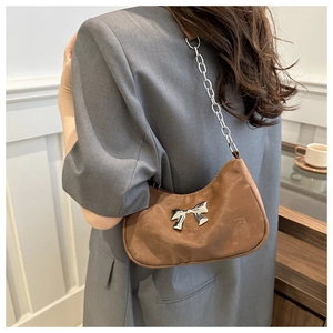 Detail of a brown crescent shoulder bag with a silk finish and silver bow buckle.