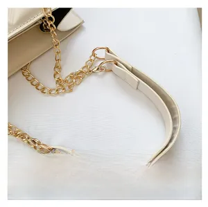 Detail of light gold chain strap with cream white faux leather shoulder pad and fine stitching