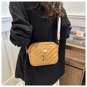 Detail of khaki quilted crossbody bag featuring a golden deer charm and wide jacquard strap