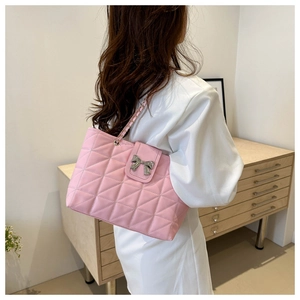 Pink quilted tote bag with bow hardware and chain strap shown on a model