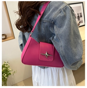 Close-up of pink underarm bag featuring a silver metal star buckle and smooth leather finish
