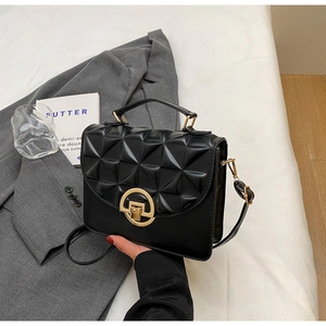 Close-up of black crossbody bag with geometric relief pattern and gold circular lock