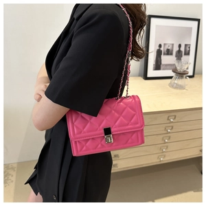 Detailed view of hot pink quilted chain bag with silver twist lock on black blazer