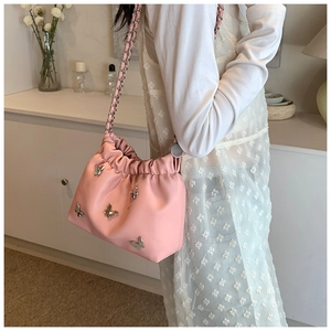 Detail der rosa Beuteltasche mit silbernen Schmetterlingsanhängern und Kettenriemen