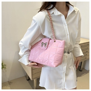 Close-up of pink quilted chain bag featuring a silver bow buckle and glossy texture