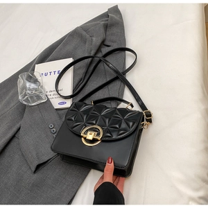 Detail of black quilted crossbody bag with golden clasp and geometric triangle stitching