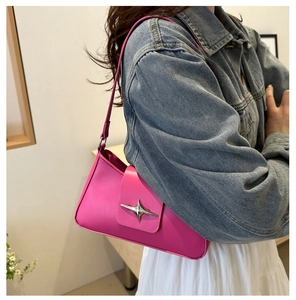 Detail of hot pink shoulder bag with silver star buckle worn with denim jacket