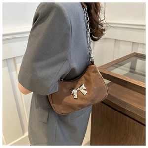 Detail of dark brown shoulder bag with large silver bow and chunky metal chain strap