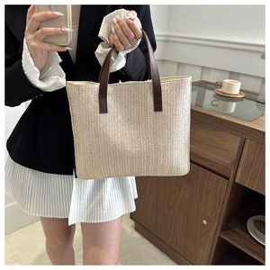 Detail of herringbone woven tote bag with dark brown leather handles for elegant commute