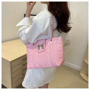 Detail of pink quilted shoulder bag featuring silver bow clasp and golden chain strap